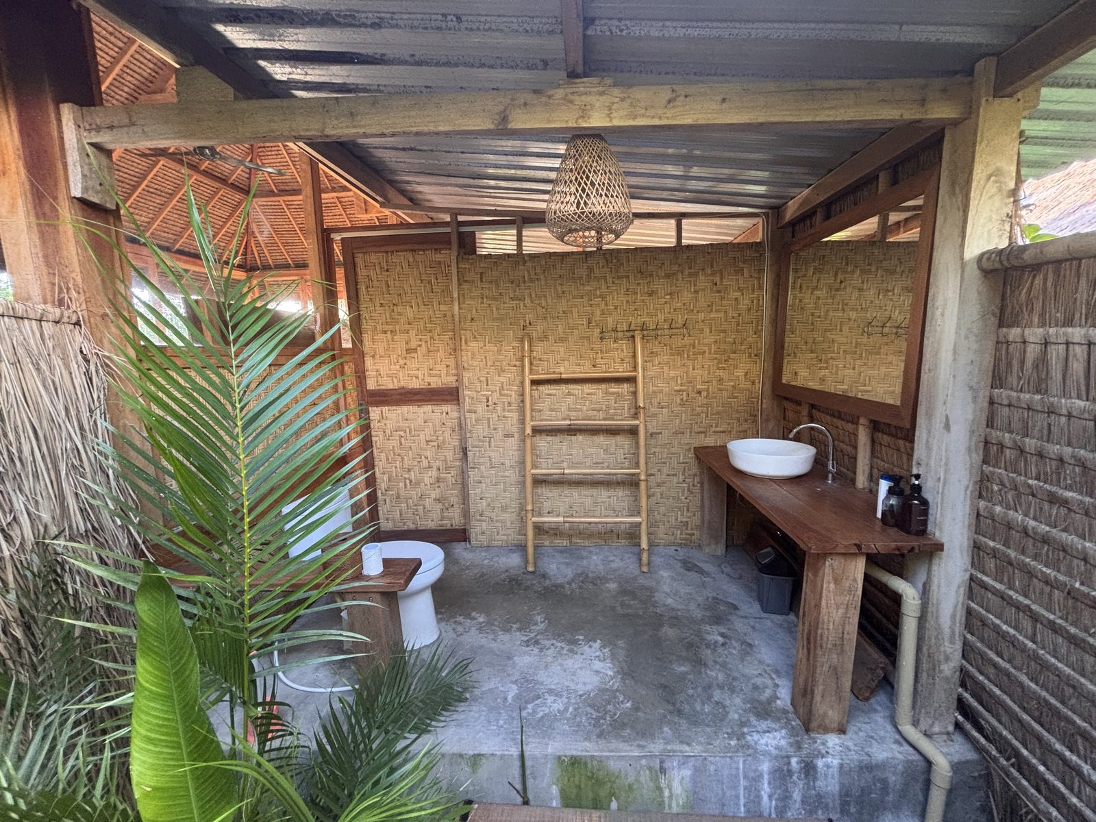 Semi-open bathroom at Small Bungalow with bamboo wall and tropical plants